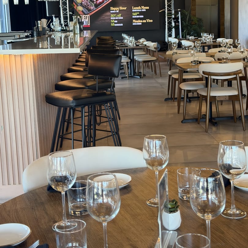 Interior of A Fuego Lento Restaurant with bar seating, dining tables, and a menu board.