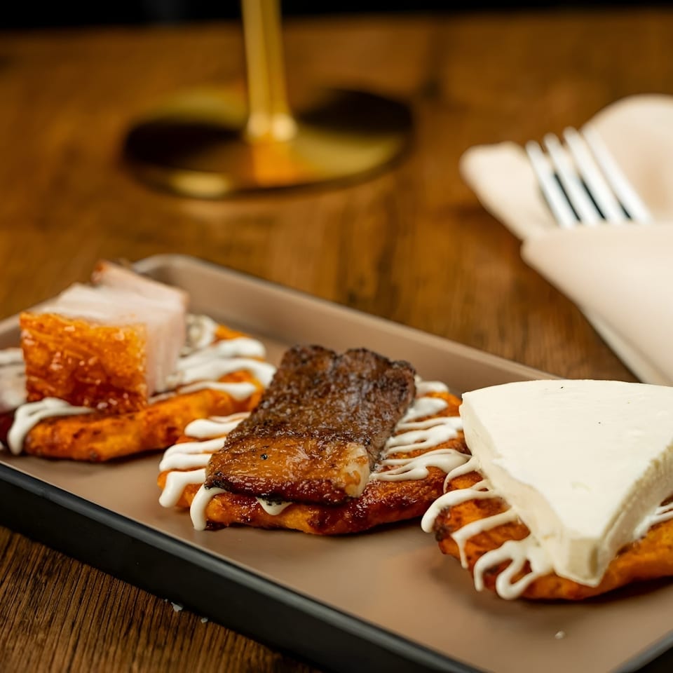 A Fuego Lento Restaurant's BBQ platter with pork belly, steak, and cheese on fried plantains.